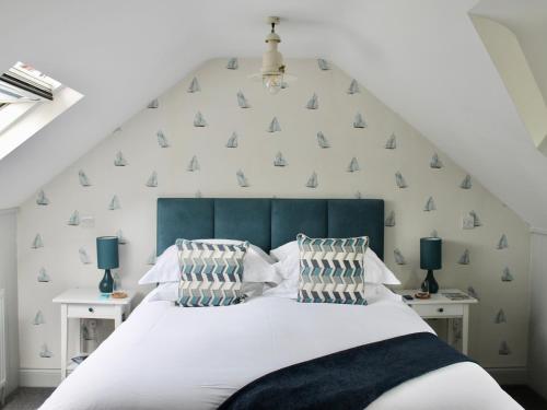 a bedroom with a white bed with a blue headboard at The Bosham Boathouse in Chichester