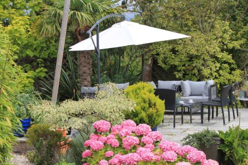 奇切斯特的住宿－The Bosham Boathouse，庭院设有椅子和遮阳伞,鲜花盛开