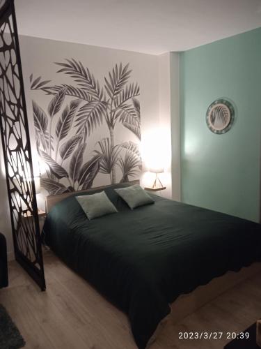 a bedroom with a bed with a plant mural on the wall at Studio plein centre face au lac in Bagnoles de l'Orne