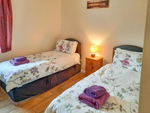 two beds in a bedroom with purple towels on them at Primrose - W43303 in Goxhill