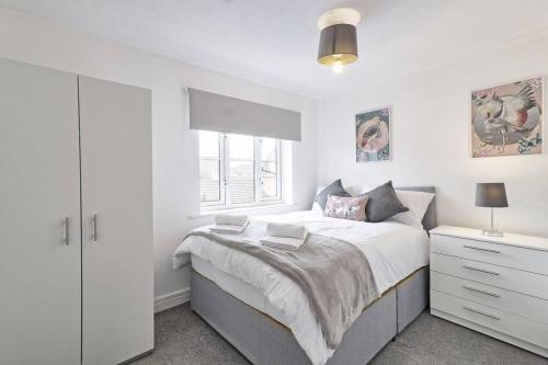 a white bedroom with a large bed and a window at Luxury 2 Bedroom House with Garden & Free Parking in West Thurrock