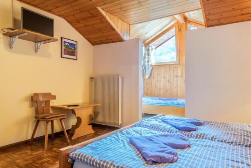 a bedroom with a bed and a desk and a window at Appartements Pension Sonia in Funes