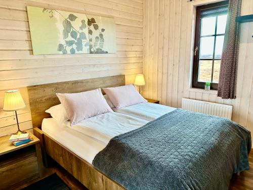 a bed in a bedroom with a wooden wall at Klettur in Borgarnes