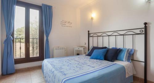 a bedroom with a bed with blue pillows and a window at Cala mezquida - 42214 Mallorca in Capdepera