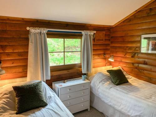 1 dormitorio con 2 camas y ventana en Squirrel View en Newtonmore