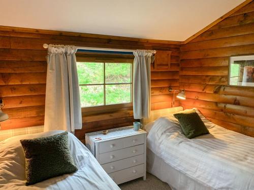 een slaapkamer met 2 bedden en een raam bij Squirrel View in Newtonmore