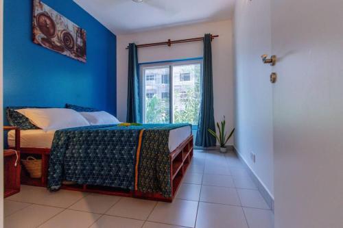 1 dormitorio con paredes azules y 1 cama con ventana en Amani Cottage, en Dambani