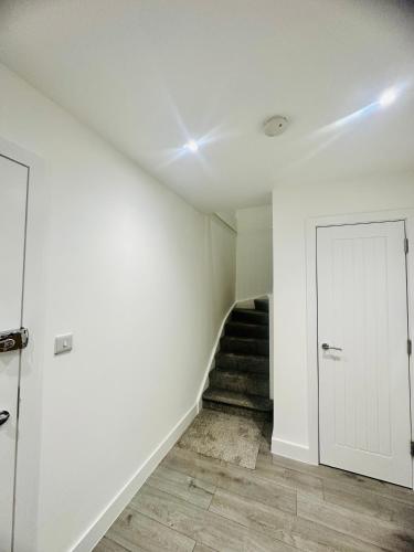 a hallway with a staircase and a white door at Hemel Apartments- Sunset retreat in Hemel Hempstead