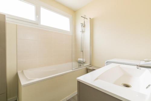 La salle de bains est pourvue d'un lavabo, d'une baignoire et d'une fenêtre. dans l'établissement LE TERROIR, au calme à deux pas du centre ville, à Dijon