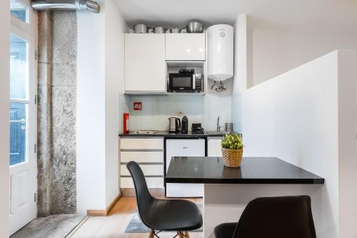 a small kitchen with a black table and chairs at Coreto Garden in Vila do Conde