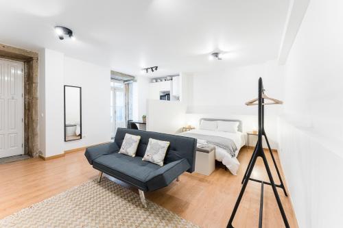 a white bedroom with a bed and a blue couch at Coreto Garden in Vila do Conde