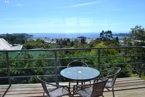 Un patio con una mesa y sillas en un balcón. en Cabañas Krause Lodge, en Puerto Varas