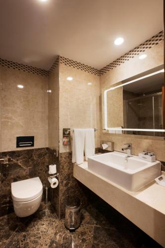 a bathroom with a sink and a toilet and a mirror at Mercure Istanbul Bakirkoy in Istanbul