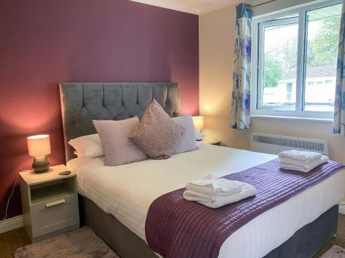 een slaapkamer met een bed met paarse muren en een raam bij Talland Bay in Saint Cleer