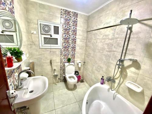 a bathroom with a toilet and a sink and a tub at ALEX HOMES - Gleem Luxury Apartments with Direct Sea View in Alexandria
