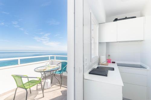 a kitchen with a table and chairs on a balcony at YourHouse Monges sea view Studio in Can Picafort