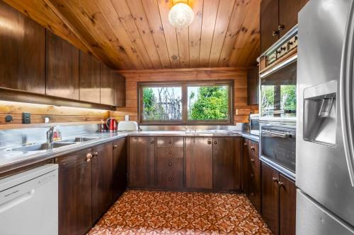 a large kitchen with wooden cabinets and a window at Lakefront Gem - Kuratau Holiday Home in Kuratau