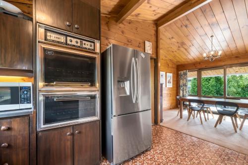 a kitchen with a stainless steel refrigerator and a table at Lakefront Gem - Kuratau Holiday Home in Kuratau