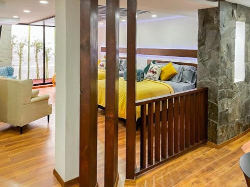 a bedroom with a yellow bed and a stone wall at Madre tierra suites tlalpujahua centro in Tlalpujahua de Rayón
