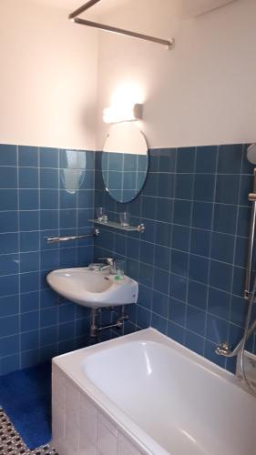 a blue tiled bathroom with a tub and a sink at Landgasthaus Lehnerwirt in Alkoven