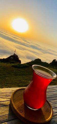 un jarrón rojo sentado en una mesa de madera con la puesta de sol en Huser Bungalov, en Rize