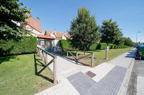 a wooden fence next to a field with a house at 158A Triplex Rinconin con piscina in Gijón