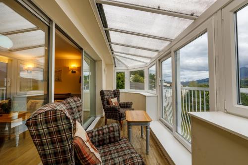 un porche cubierto con 2 sillas y ventanas en Loch Rannoch Highland Club en Kinloch Rannoch