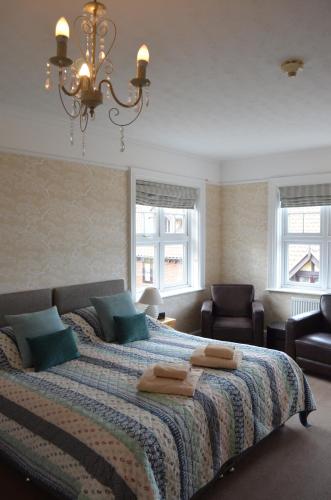 a bedroom with a bed and two chairs and a chandelier at Camberley House in Sheringham