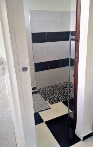 a bathroom with a shower with a black and white tile floor at Jolie studette dans un environnement arboré in Les Abymes