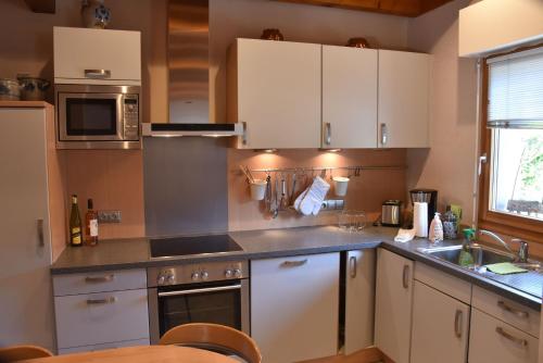 a kitchen with white cabinets and a sink at La maison chez Doris et Francis in Thanvillé