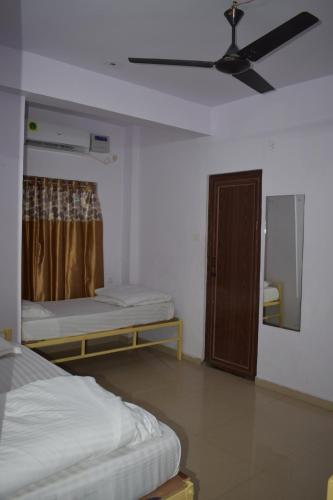 a room with two beds and a ceiling fan at HOTEL PURI GREENS in Puri