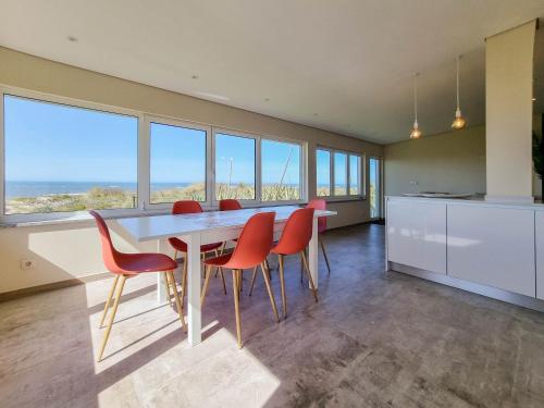 a dining room with a table and chairs and windows at Pé No Mar - sea view in Viana do Castelo