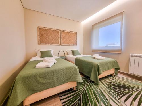 a room with two beds with green blankets and a window at Pé No Mar - sea view in Viana do Castelo