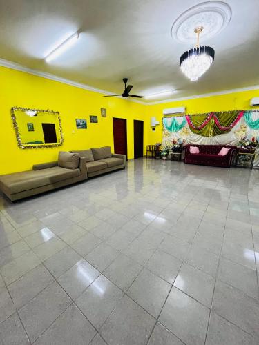 a living room with a couch and a yellow wall at Homestay/Bilik Teluk Gading in Kuala Rompin