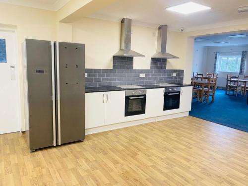 a kitchen with a stainless steel refrigerator in a room at En-suites Rooms in Northampton in Moulton