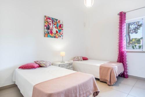 two beds in a room with a window at Villa Patio in Albufeira