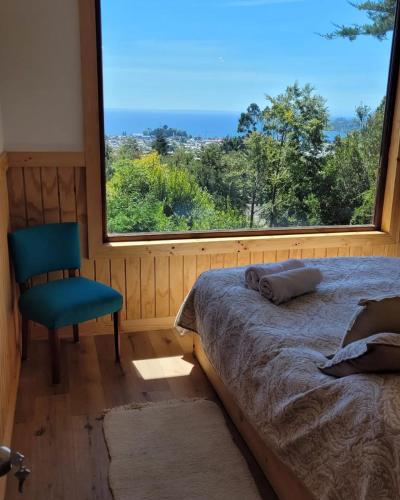 a bedroom with a bed and a chair and a window at Cabañas Krause Lodge in Puerto Varas