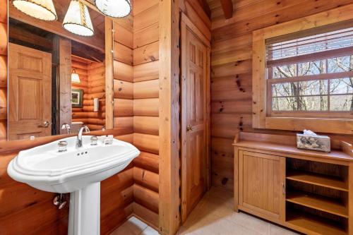 baño en una cabaña de madera con lavabo y ventana en Rustic Elegance, en Boone