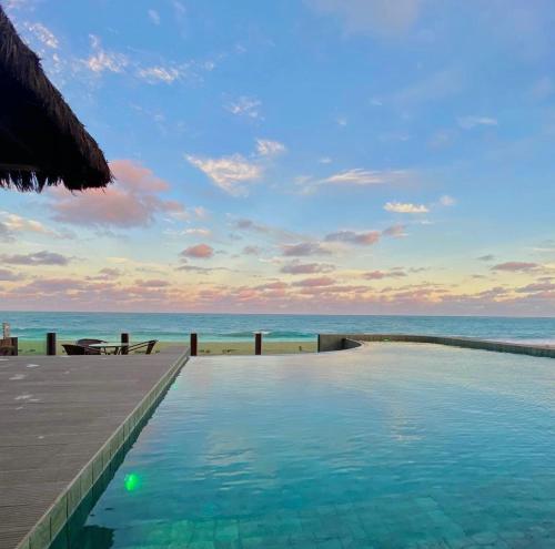 a swimming pool with the ocean in the background at Pousada Maracabana Spa in Porto De Galinhas