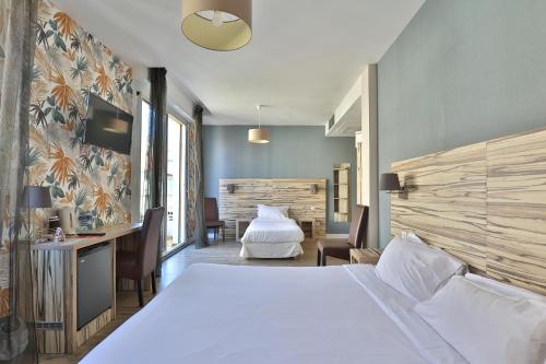 - une chambre avec un grand lit blanc et un bureau dans l'établissement Brit Hotel Marbella, à Biarritz