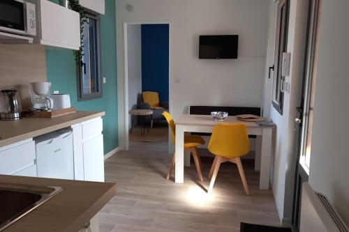 une petite cuisine avec une table et des chaises jaunes dans l'établissement Le Clos Duthu, Ideal curistes, à Bagnères-de-Bigorre