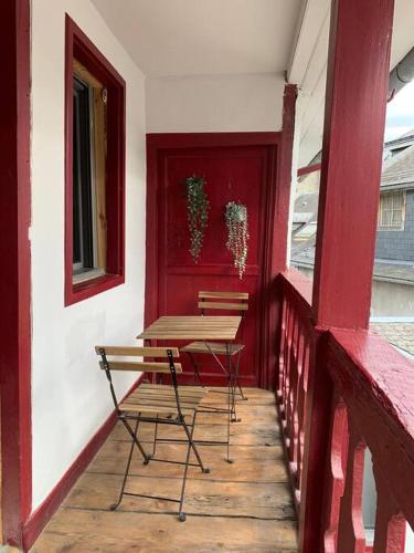 een tafel en stoelen op een veranda met een rode muur bij Le Clos Duthu, Ideal curistes in Bagnères-de-Bigorre