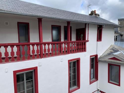 een wit gebouw met rode ramen en een balkon bij Le Clos Duthu, Ideal curistes in Bagnères-de-Bigorre