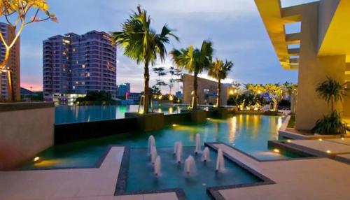 a swimming pool with palm trees and buildings at Meta @ Swiss Garden Residence KL Bukit Bintang in Kuala Lumpur