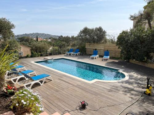 une piscine avec des chaises bleues et une terrasse en bois dans l'établissement Villa Romuald, à Sainte-Maxime
