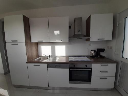 a kitchen with white cabinets and a sink at Villa-kuća za odmor "RATAC" in Bol