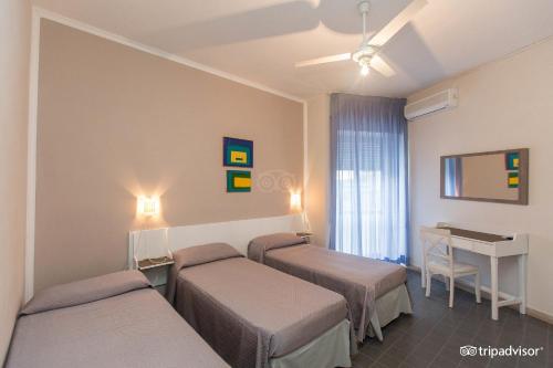 a hotel room with three beds and a desk at Hotel Anna in Terracina