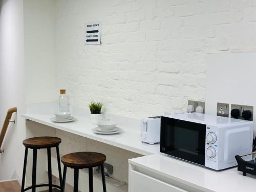une cuisine avec un comptoir, un four micro-ondes et deux tabourets dans l'établissement The Grand M London city, à Londres