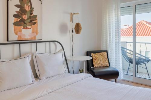 a bedroom with a bed and a chair and a window at Charroque in Setúbal