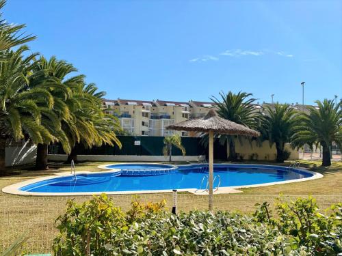 a swimming pool with an umbrella and palm trees at Caleta Vyb in Denia